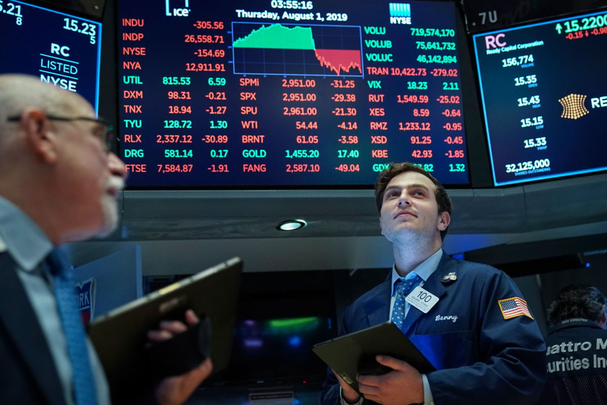 A stock broker looks onward as a diagram showing plummeting stocks is displayed behind him