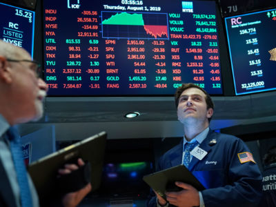 A stock broker looks onward as a diagram showing plummeting stocks is displayed behind him