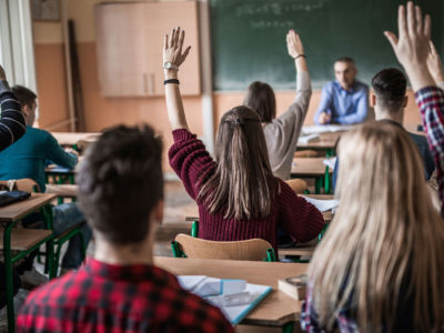 Students raise hands in class