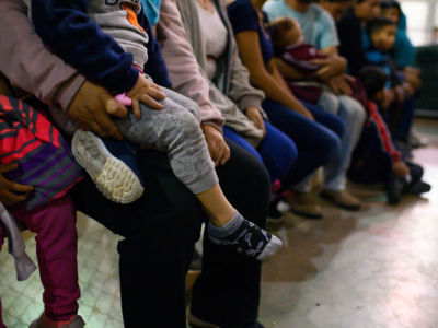 Legs and feet of migrants sitting on a bench, immigration