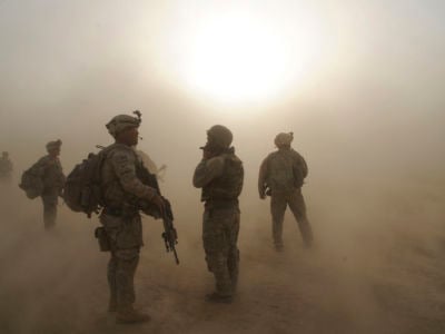 Soldiers stand amidst clouds of dust