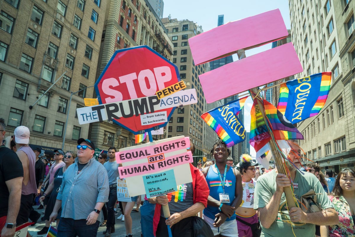 Queer activists display anti-trump signs during a march