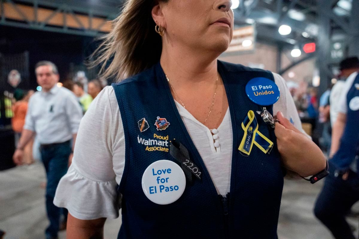 A woman wears a walmart vest with various pieces of flair commemorating the victims of the mass shooting in el Paso, Texas.