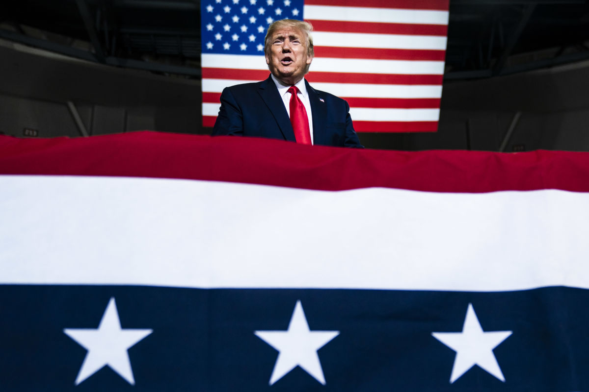 Dondald trump speaks behind a u.s. flag