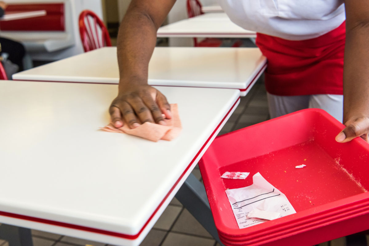 Restaurant worker cleans crumbs off of a table