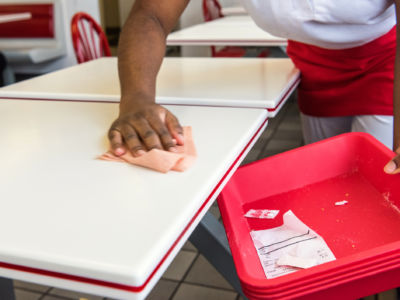 Restaurant worker cleans crumbs off of a table