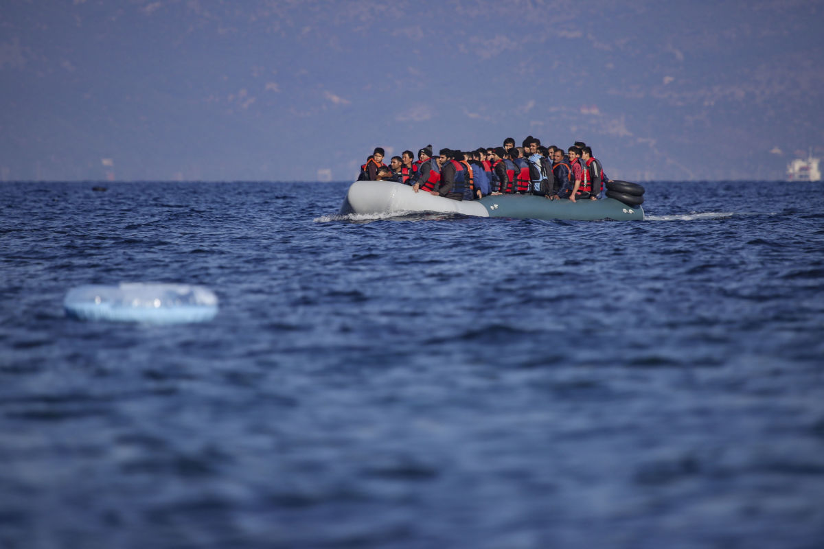 Migrants, some with orange life vests, are seen in a small raft