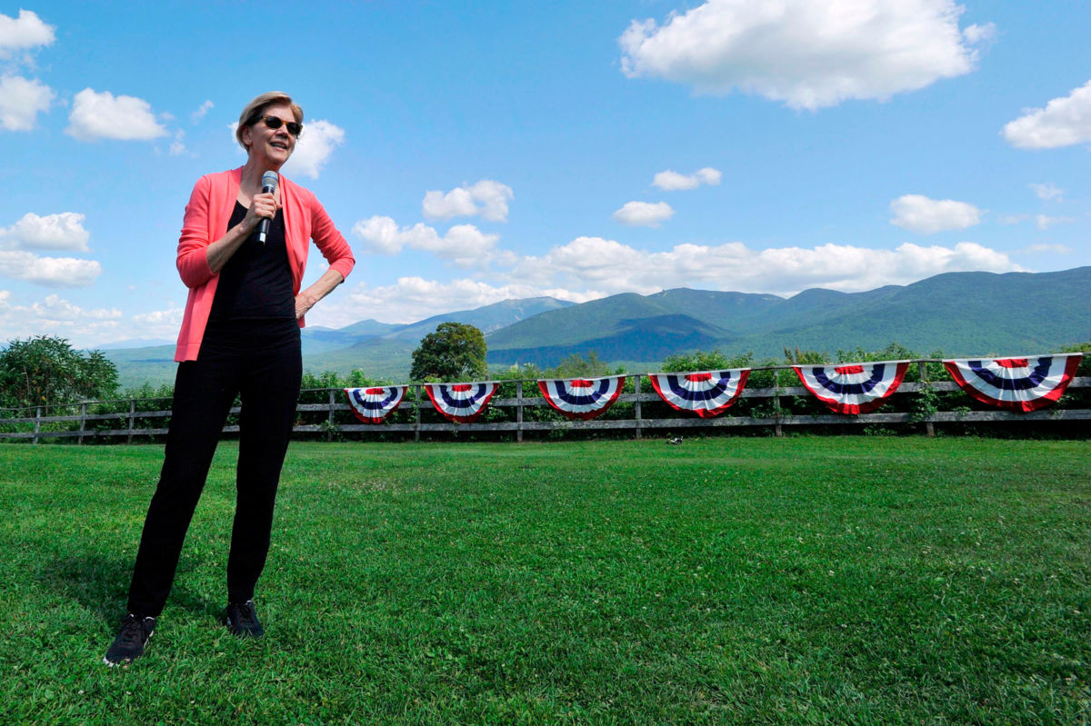 Elizabeth Warren stands in a field with a microphone
