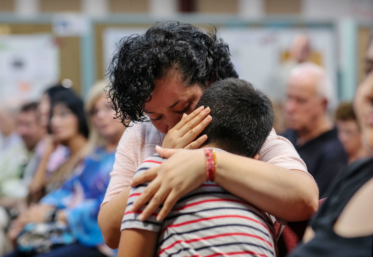 A mother comforts her child during a town-hall meeting