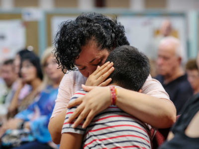 A mother comforts her child during a town-hall meeting