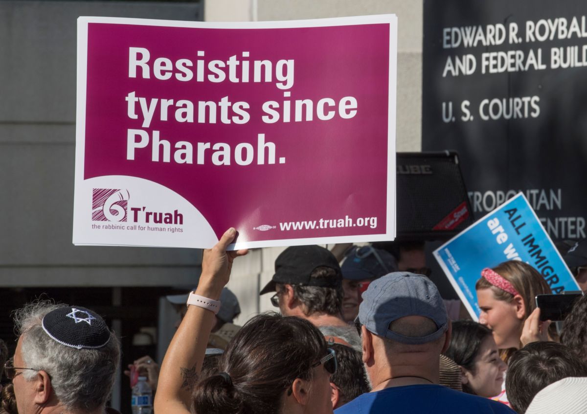 A protester holds a sign reading "Resisting tyrants since Pharoah" during a protest