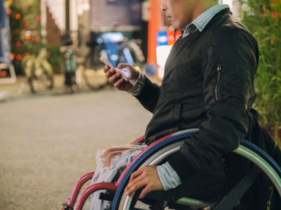 A man in a wheelchair checks his phone