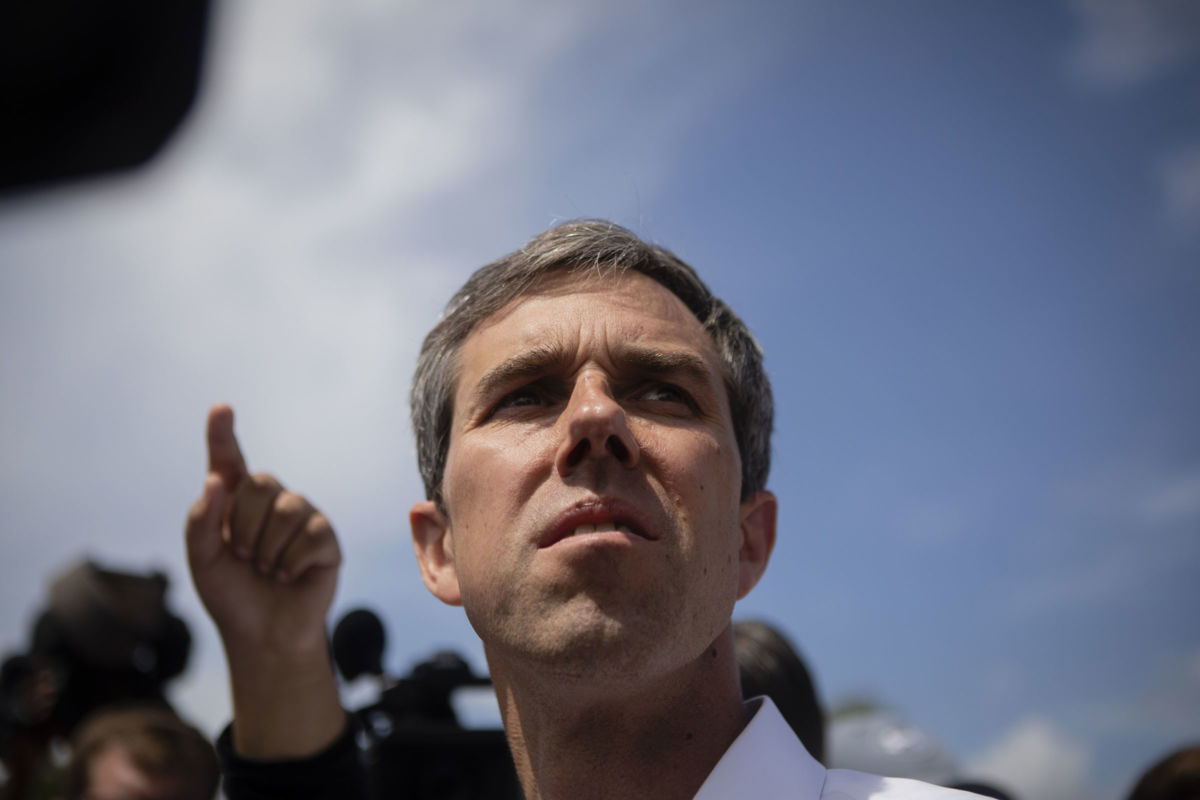 Beto O'Rourke looks up at the sky while surrounded by people