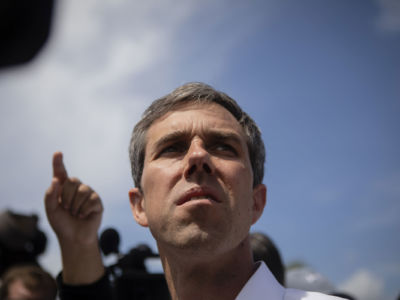 Beto O'Rourke looks up at the sky while surrounded by people