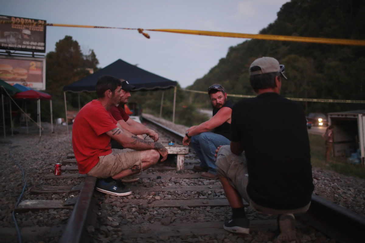 Men sit on railroad tracks cordoned off with police tape