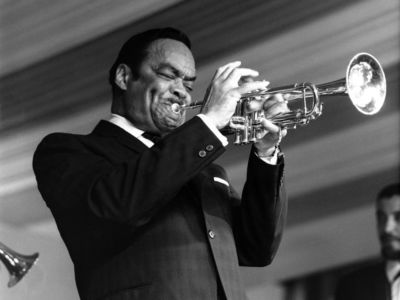 Buck Clayton plays the trumpet in a black and white photo