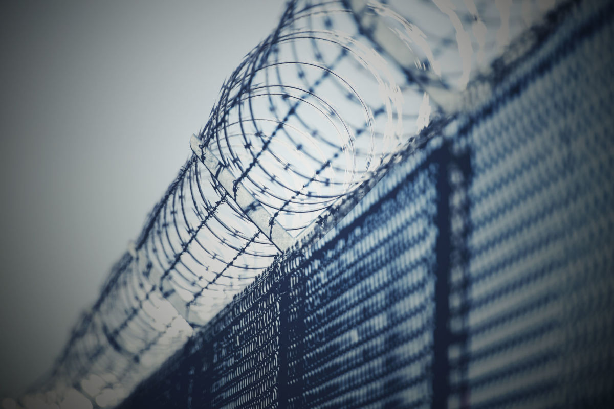 Spirals of razor wire wrap around the top of a chain-link fence