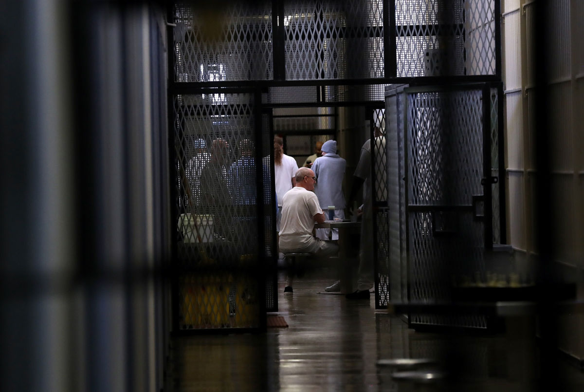 Prisoners are seen through several sets of prison fencing and doors