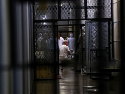 Prisoners are seen through several sets of prison fencing and doors