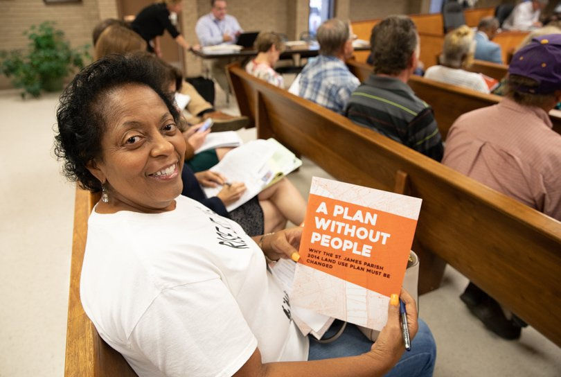 A woman smiles while holding a pamphlet