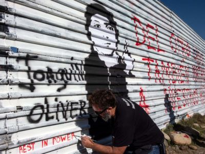 Venezuelan artist Manuel Oliver, father of slain Joaquin Oliver, works on a mural on the U.S.-Mexico border fence reading "On the other side they also kill our sons" in Tijuana, Baja California State, Mexico, on December 19, 2018.