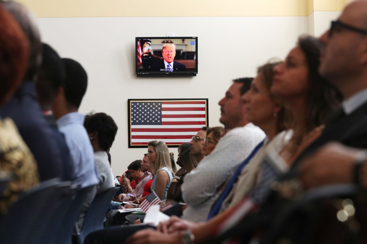 President Donald Trump is seen on a television screen as he makes a taped speech during a ceremony for people to become American citizens at a U.S. Citizenship and Immigration Services naturalization ceremony in a Miami Field Office on August 16, 2019, in Miami, Florida.