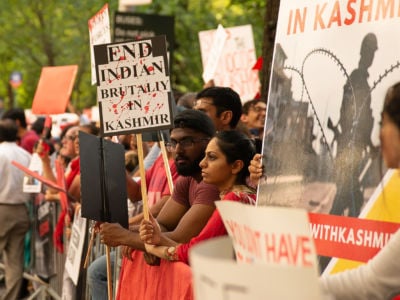 People display signs during a protest in solidarity with Kashmir