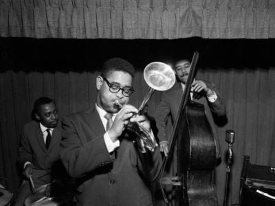 Jazz legend Dizzy Gillespie playing the trumpet with two other band members in 1955.