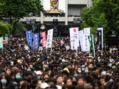 Thousands of black-clad protesters march through the streets carrying signs