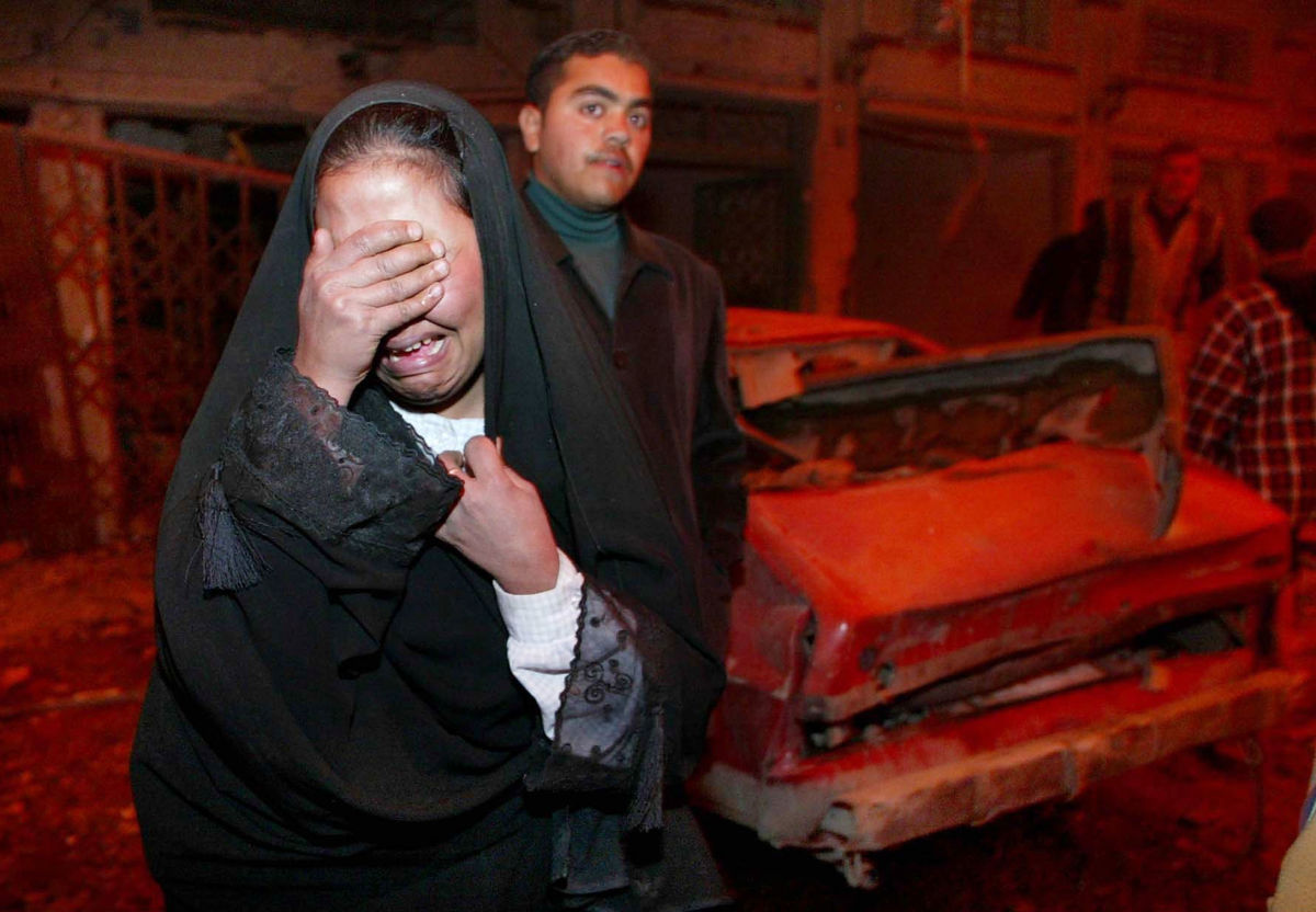 A woman wails into her hands amongst rubble from an airstrike