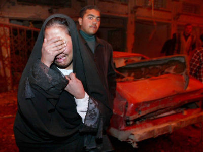 A woman wails into her hands amongst rubble from an airstrike