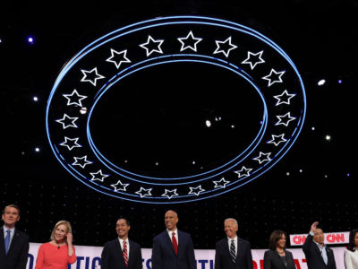 Presidential candidates stand next to oneanother and greet the crowd at a debate