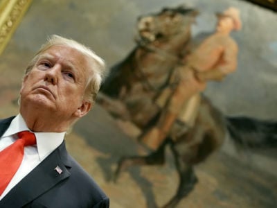 Donald Trump looks onward in front of a painting of Teddy Roosevelt