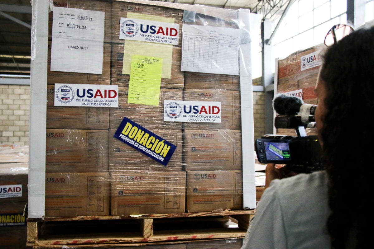 A person looks at wrapped up boxes marked "USAID"