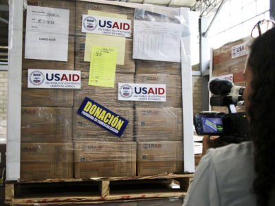 A person looks at wrapped up boxes marked "USAID"