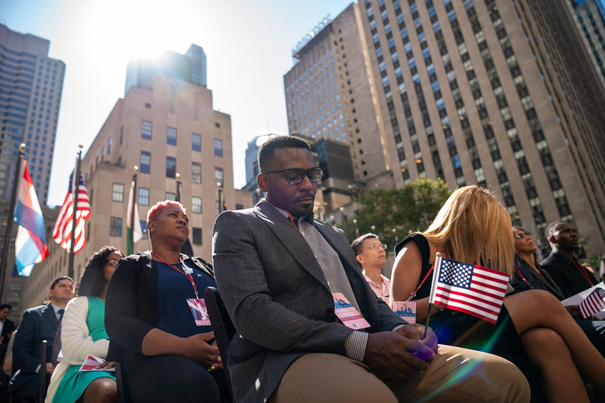 A man holds a tiny u.s. flag during an outdoor assembly