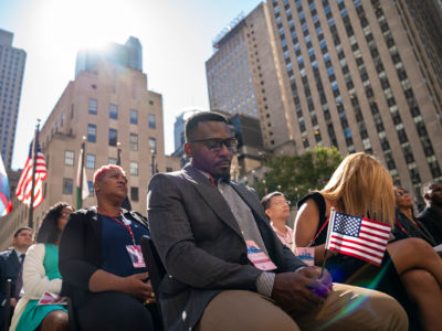 A man holds a tiny u.s. flag during an outdoor assembly