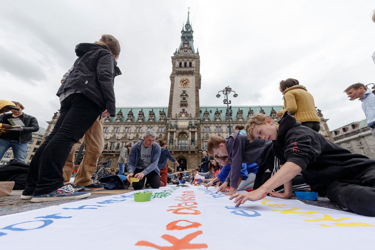 Teens paint a huge banner in preparation for a climate action