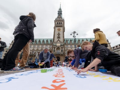 Teens paint a huge banner in preparation for a climate action