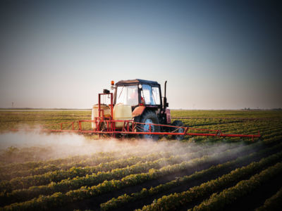 A tractor sprays fields of crops