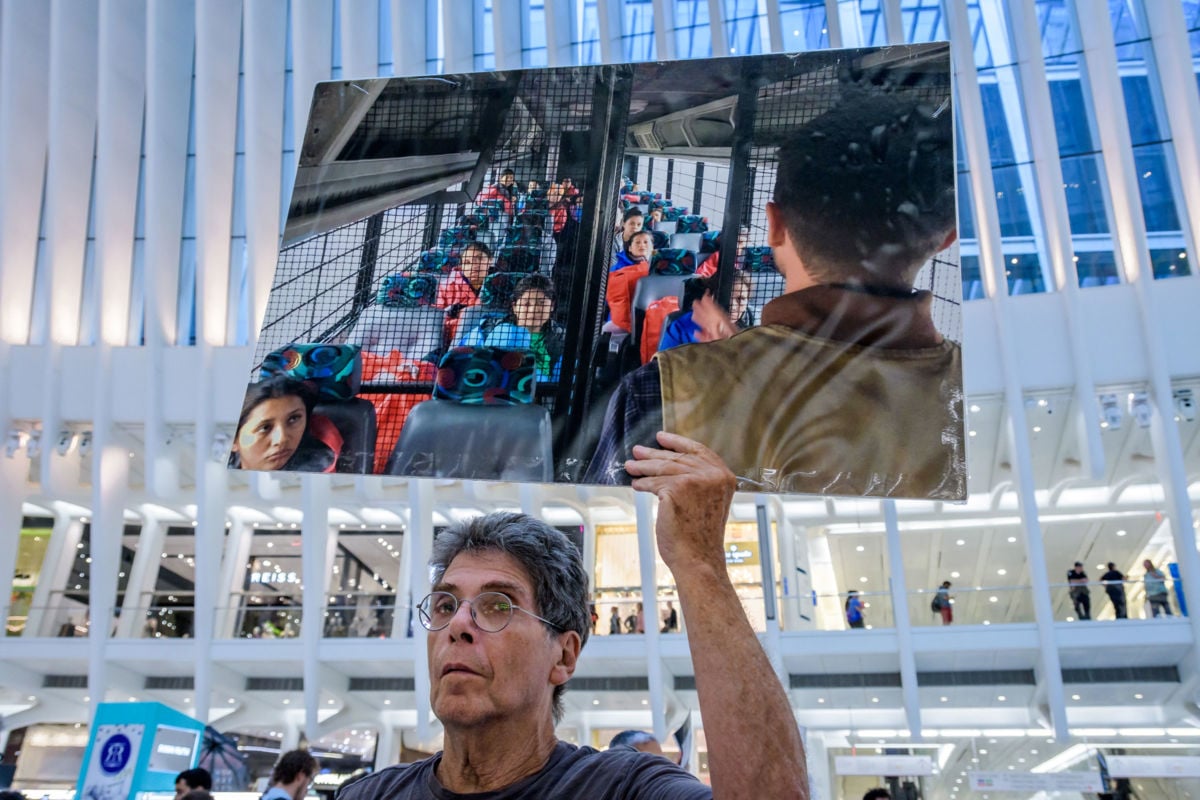 A protester holds an enlarged photo of a prison bus filled with children