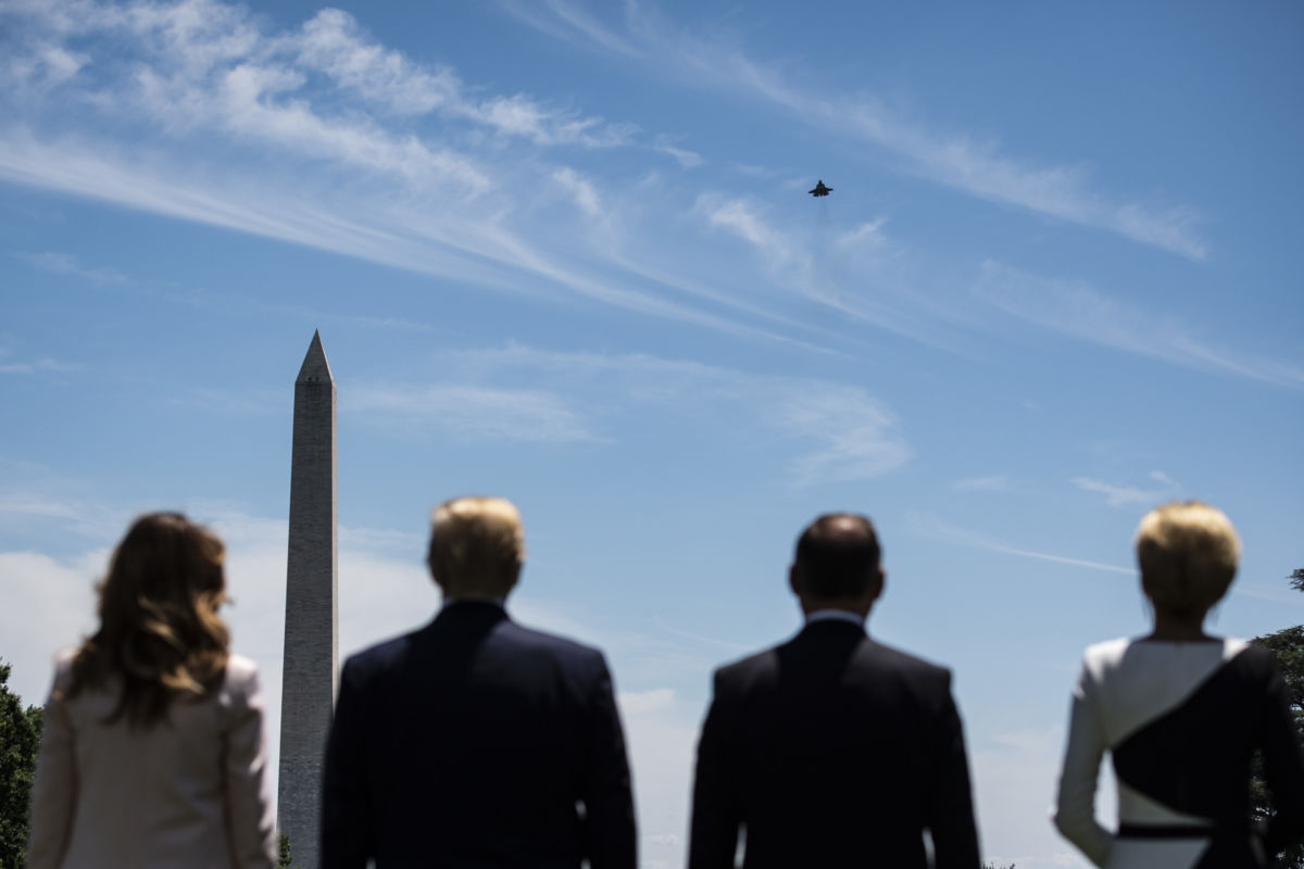Melania, trump, and two others watch a lockheed martin jet in the sky