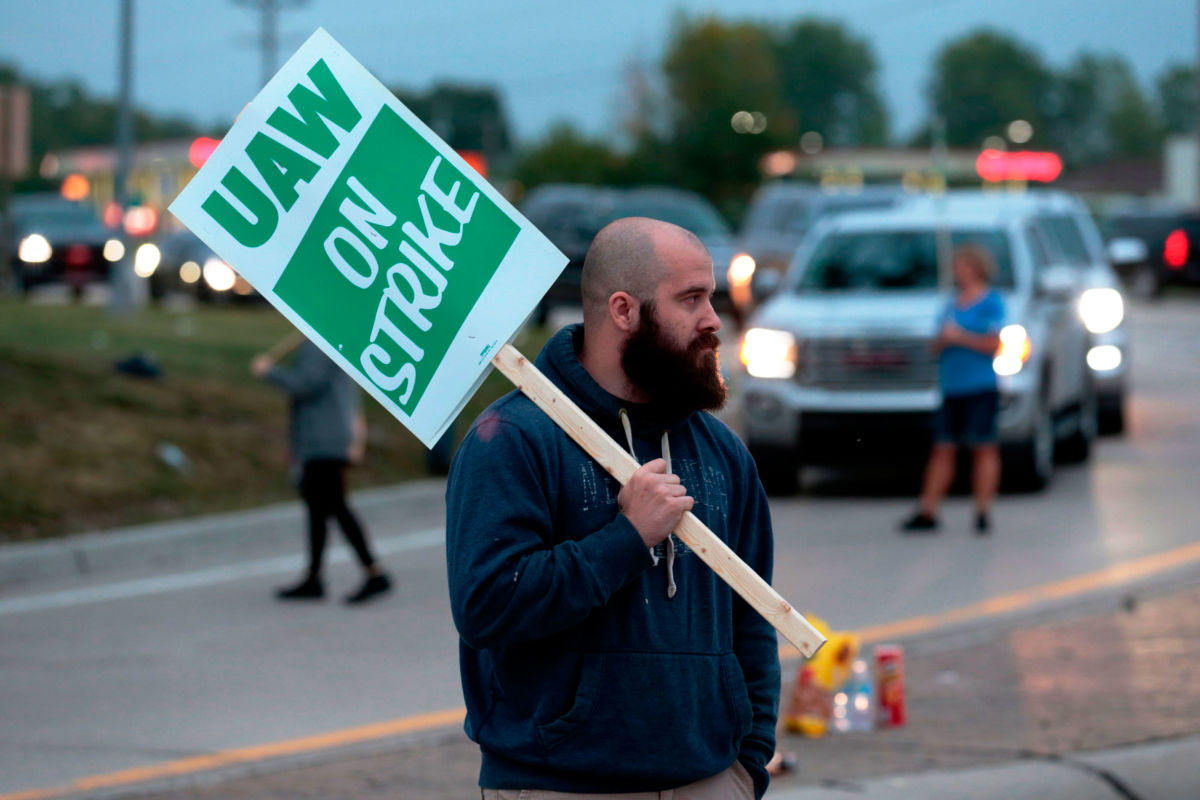 A man holds a sign reading "UAW ON STRIKE"