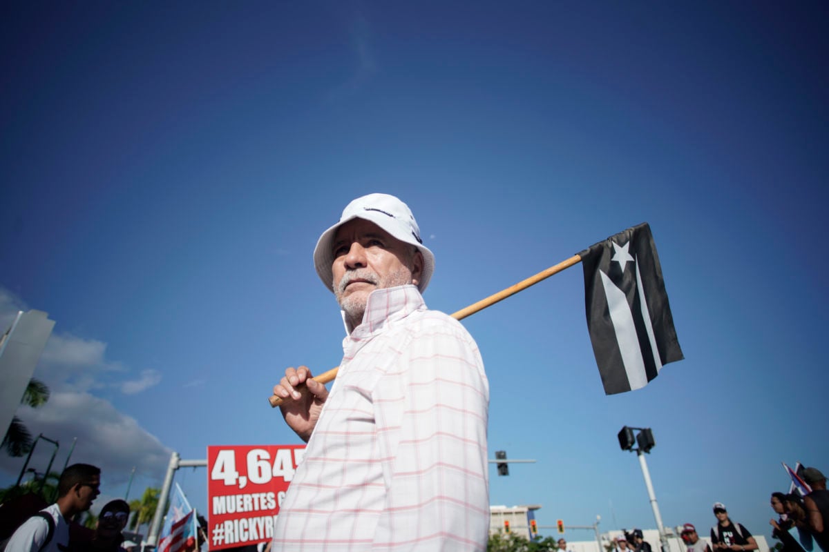 A man holds a black and white Puerto Rican flag during a protest