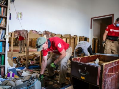 Workers in red shirts clear debris from a damaged church damaged during hurricane dorian