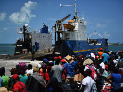 People wait on a dock to be able to board a ship to the U.S.
