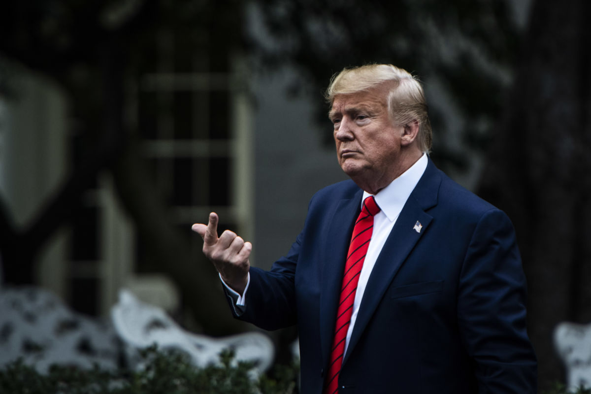 Donald Trump gestures while standing in front of the white house