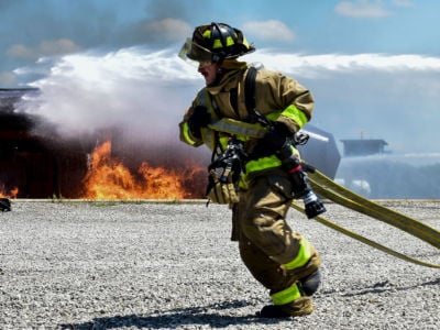 An Army firefighter stationed in Mansfield, Ohio, rushes to unravel a fire hose during a rescue firefighting exercise.