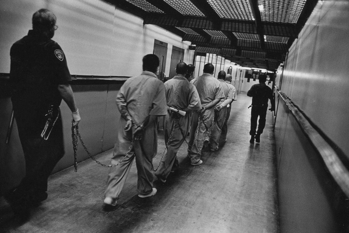 A group of men is led down a hallway in California's Pelican Bay prison, where many people spend years in solitary confinement and only leave their cells with full chains on.