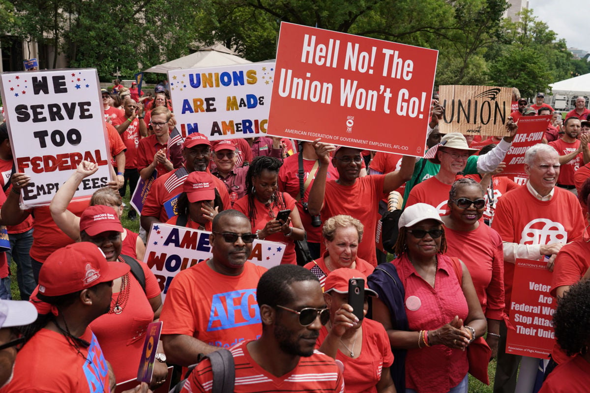 Workers wearing red shirts display signs during a protest